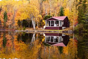 Reflections of a autumn forest and a house in a lake. Red house in background.