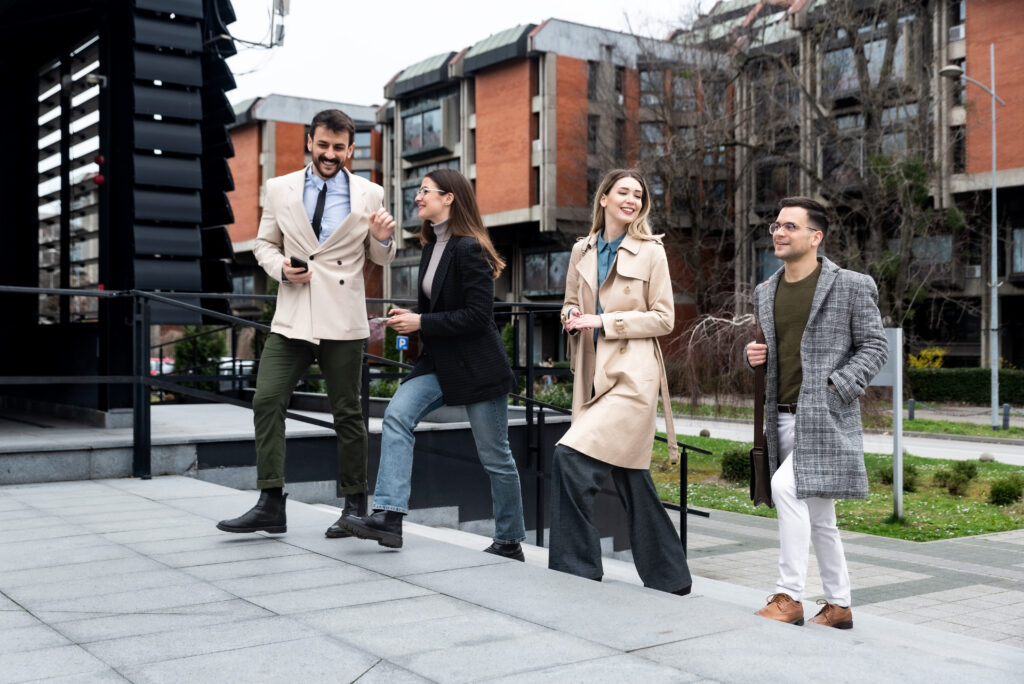 A group of young professionals, two men and two women, walk up outdoor stairs on the way to work.
