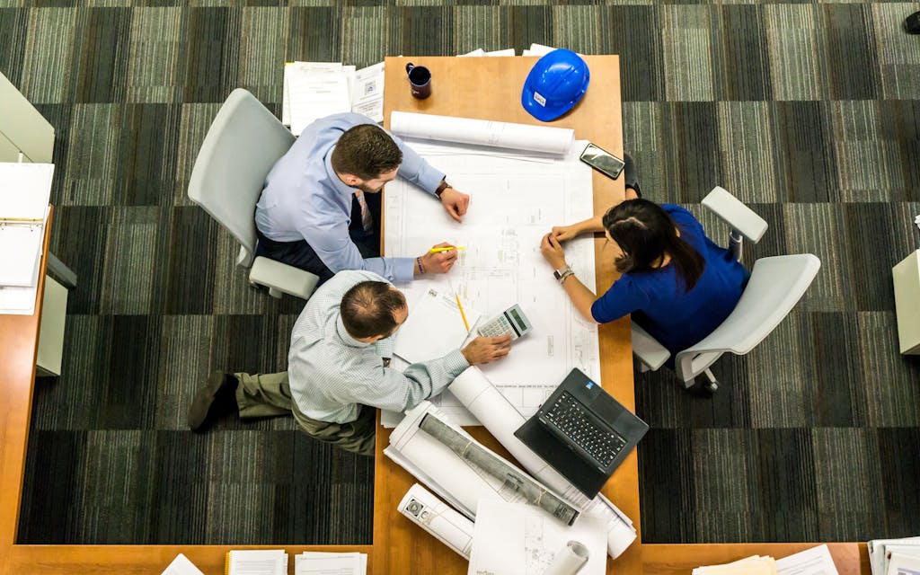 Three People Sitting at a table reviewing a construction design